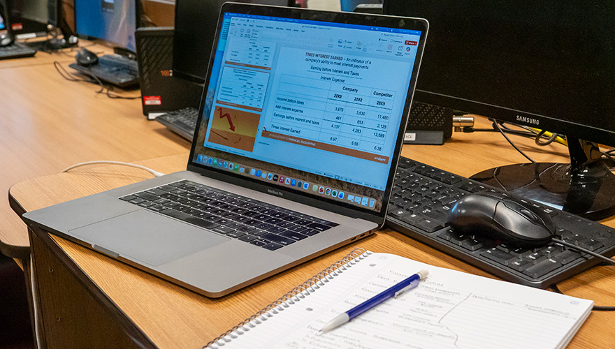 Open laptop showing a table with numbers and a graph with a notebook and pen next to it