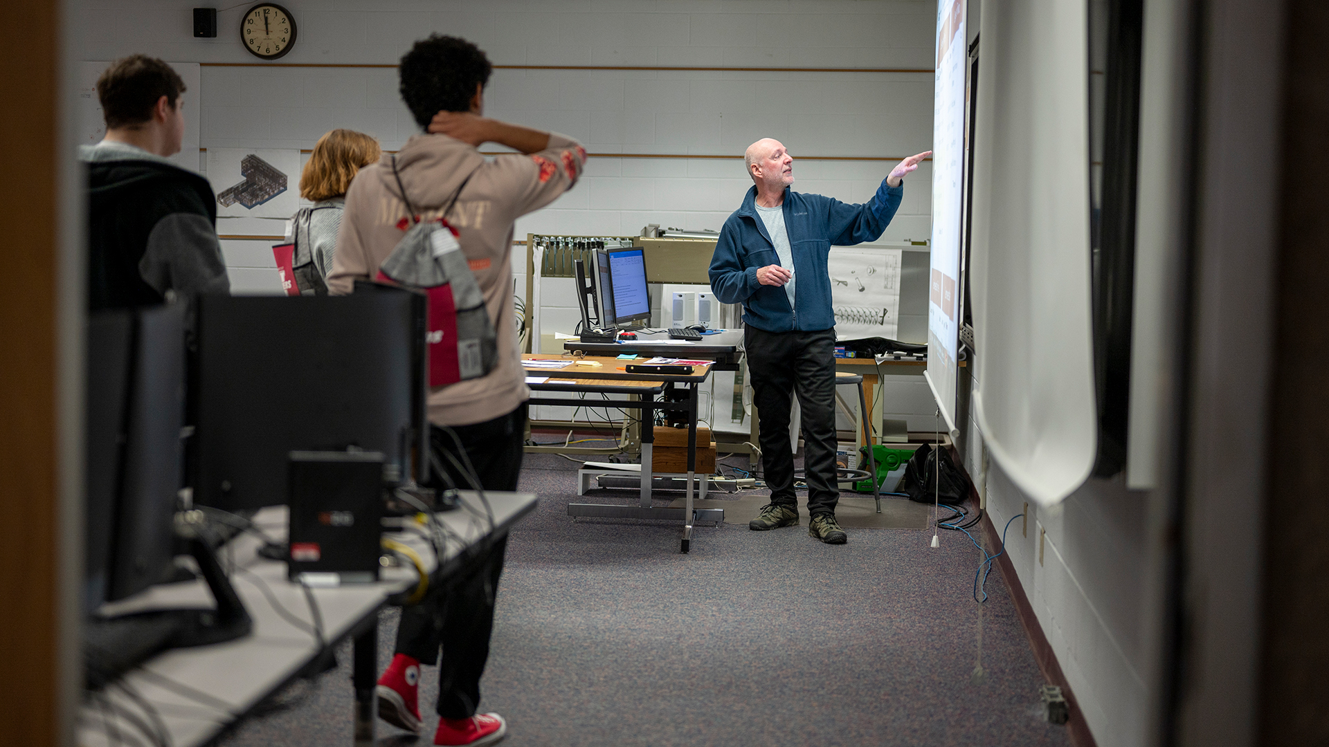 Professor pointing to a board with high school students watching