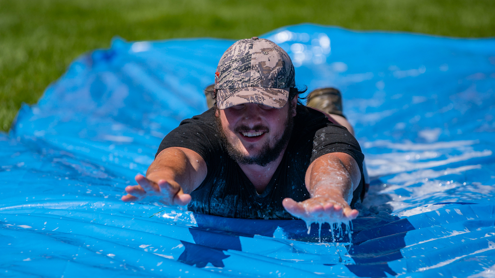 Male student sliding down a slip and slide