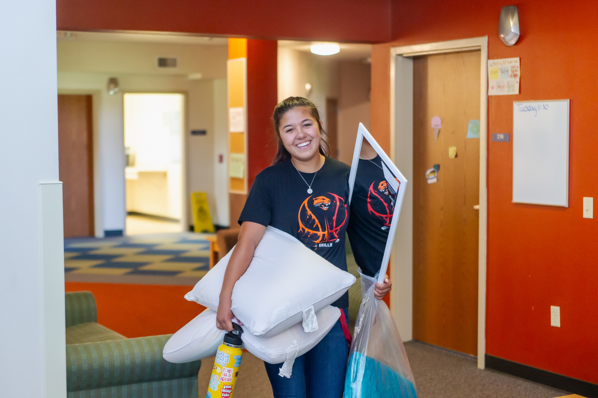 Female student moving in carrying pillows and a mirror