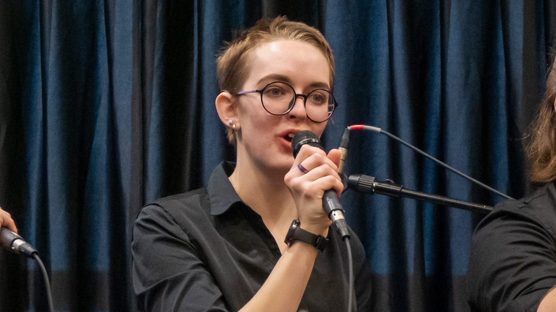 A girl in a black shirt singing while holding a microphone