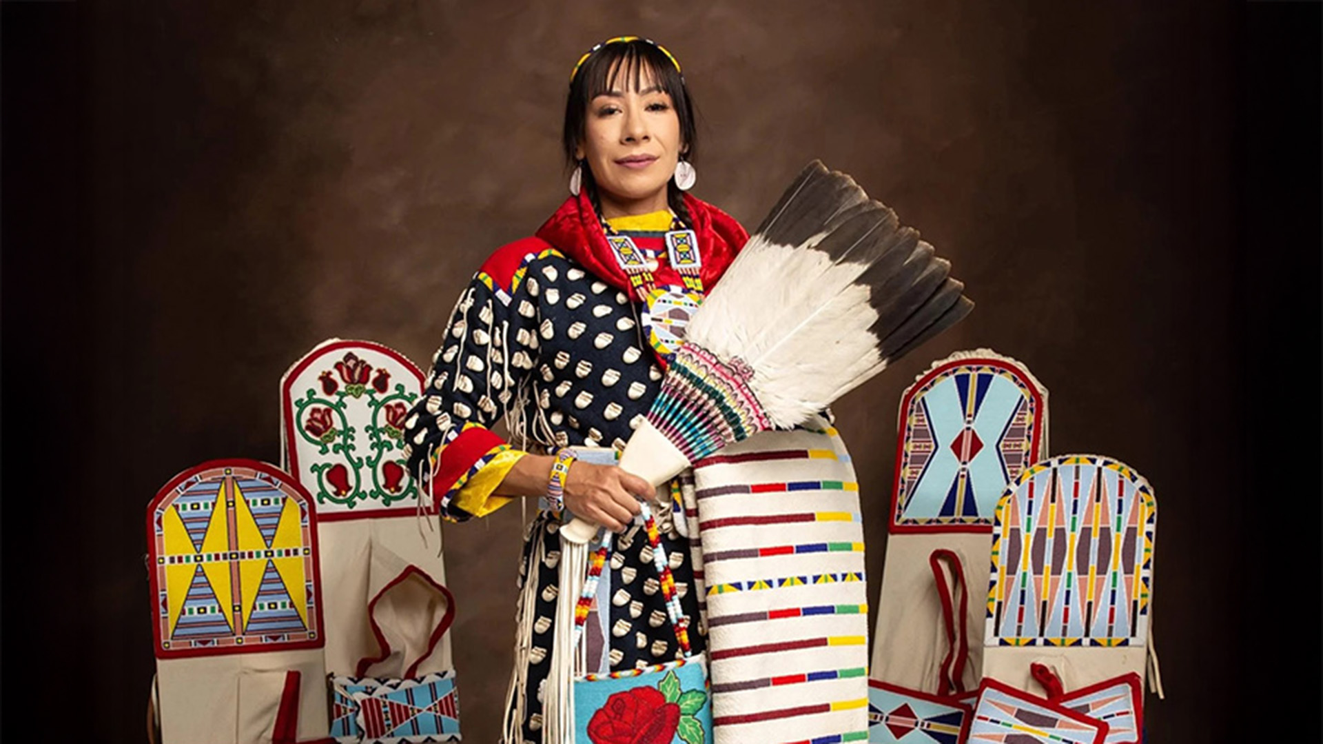 A Native American woman posing with traditional cradleboards around her