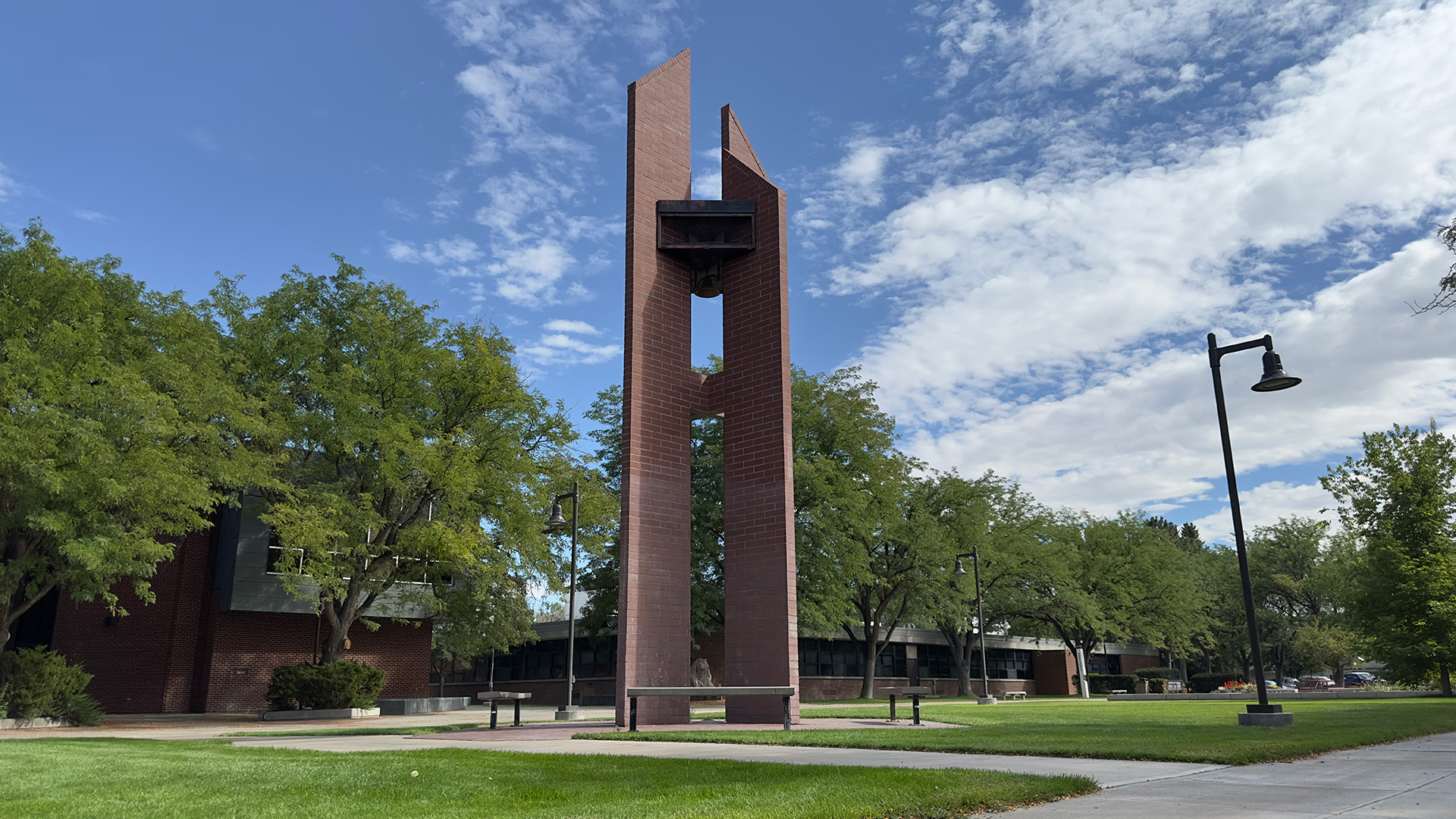 The college carillon as seen from ground level against partly cloudy blue sky surrounded by trees and green grass