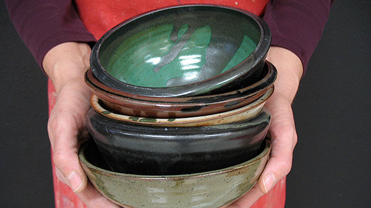 A woman's hands holding a stack of ceramic bowls