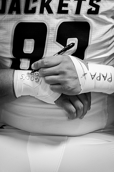 A football player writing notes on tape around his wrists