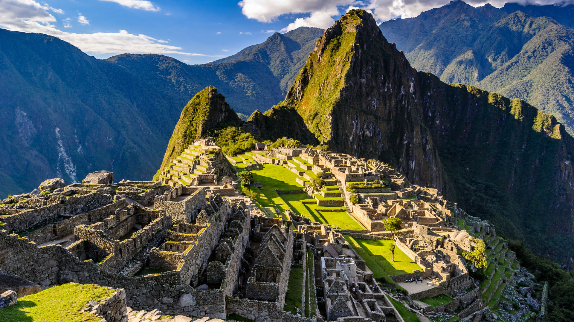 Aerial view of Machu Picchu at sunrise in the Andes Mountains with the ruins beneath a tall peak