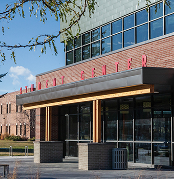 Front view of student center building with red lettering on roof overhang above front entrance with reflections off second tory windows