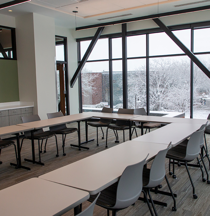 Meeting room with chairs around a group of tables and snow covered grounds outside