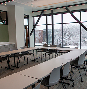 Meeting room with chairs around a group of tables and snow covered grounds outside