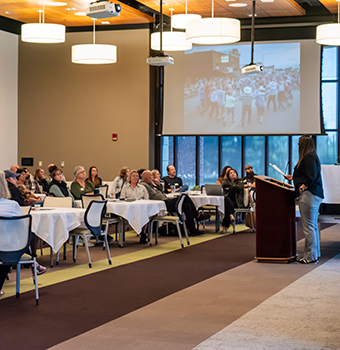 A room full of people listening to a speaker at a podium