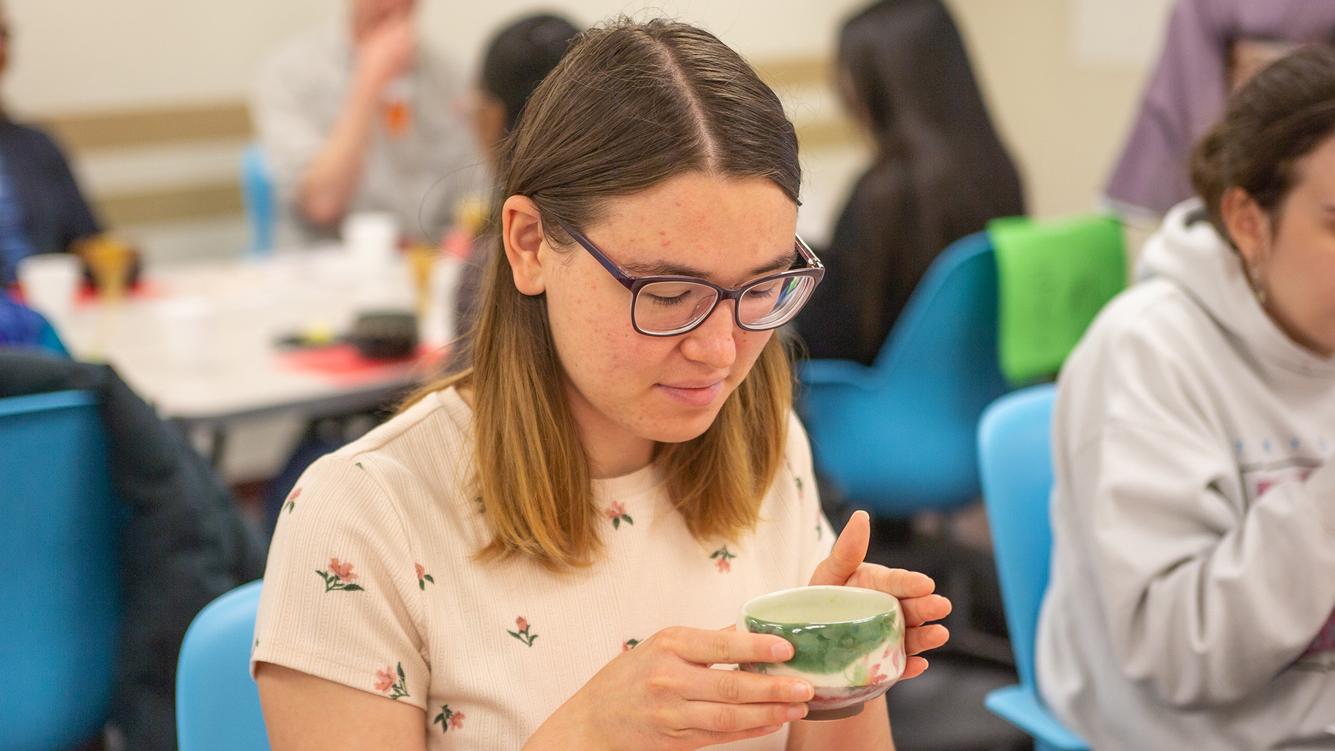 A female college student holding and looking down at a cup of tea