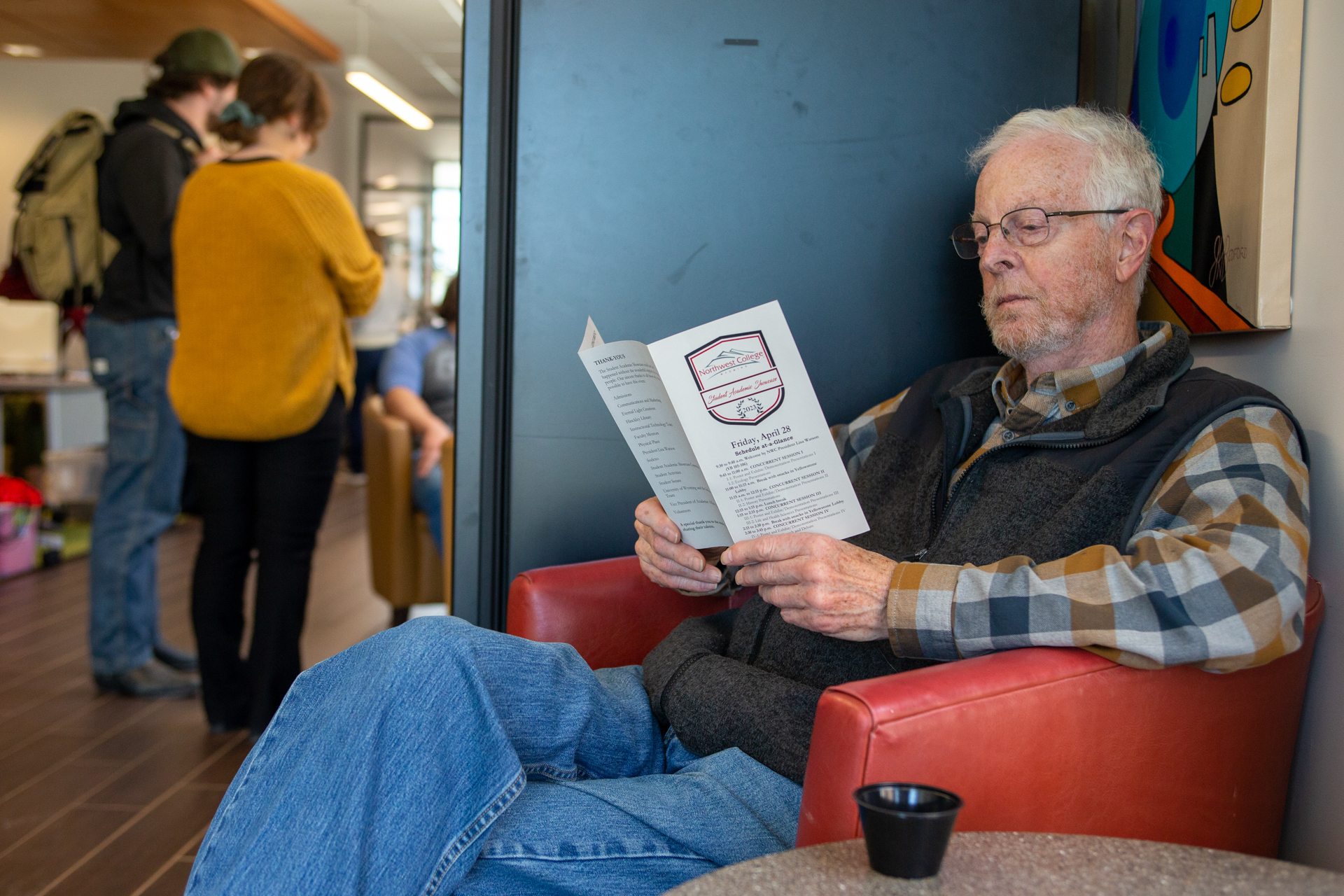 Emeriti faculty Alan Childs sitting in a chair reading a program