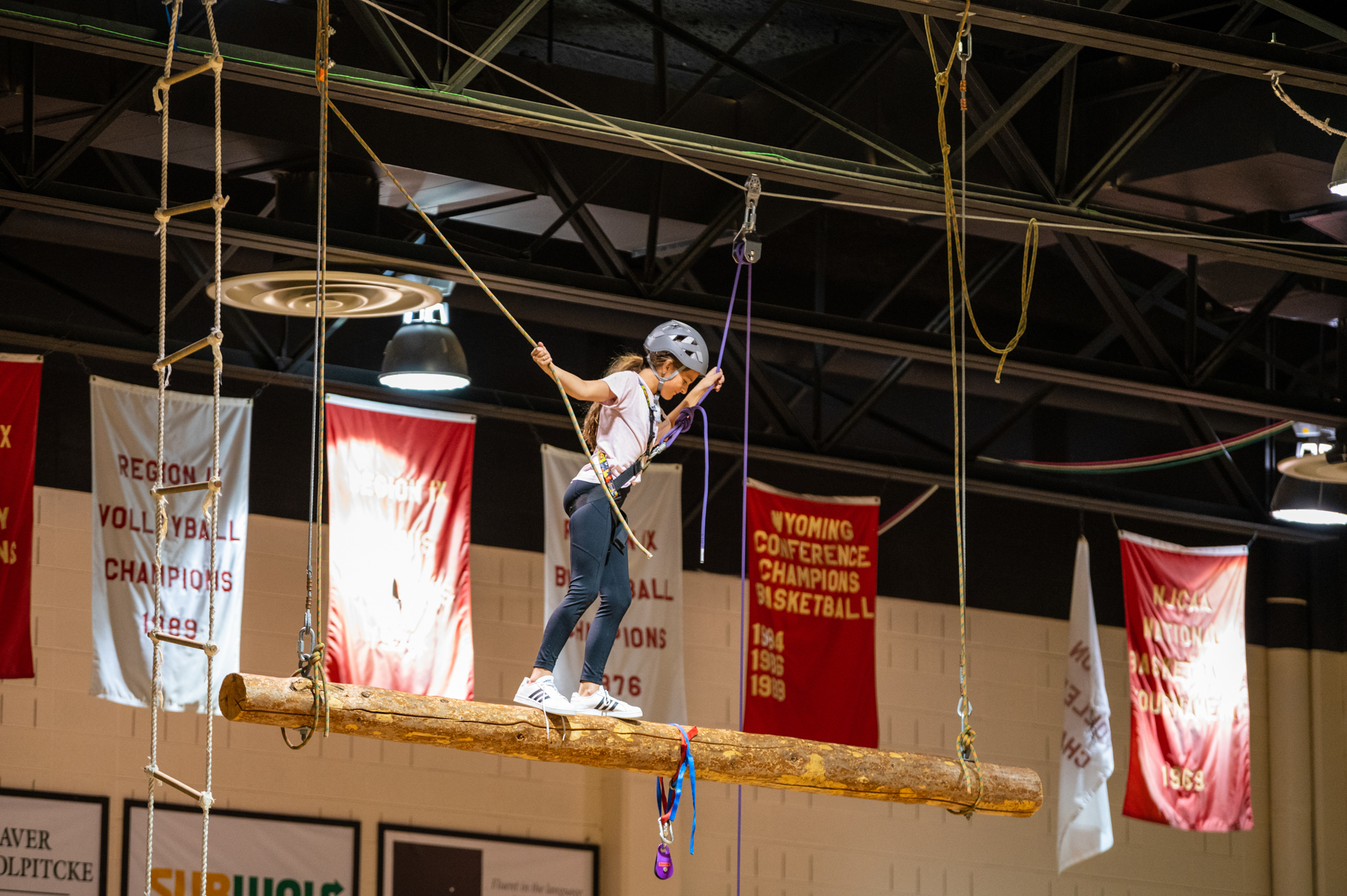 Girl balancing on a log hanging between two ropes