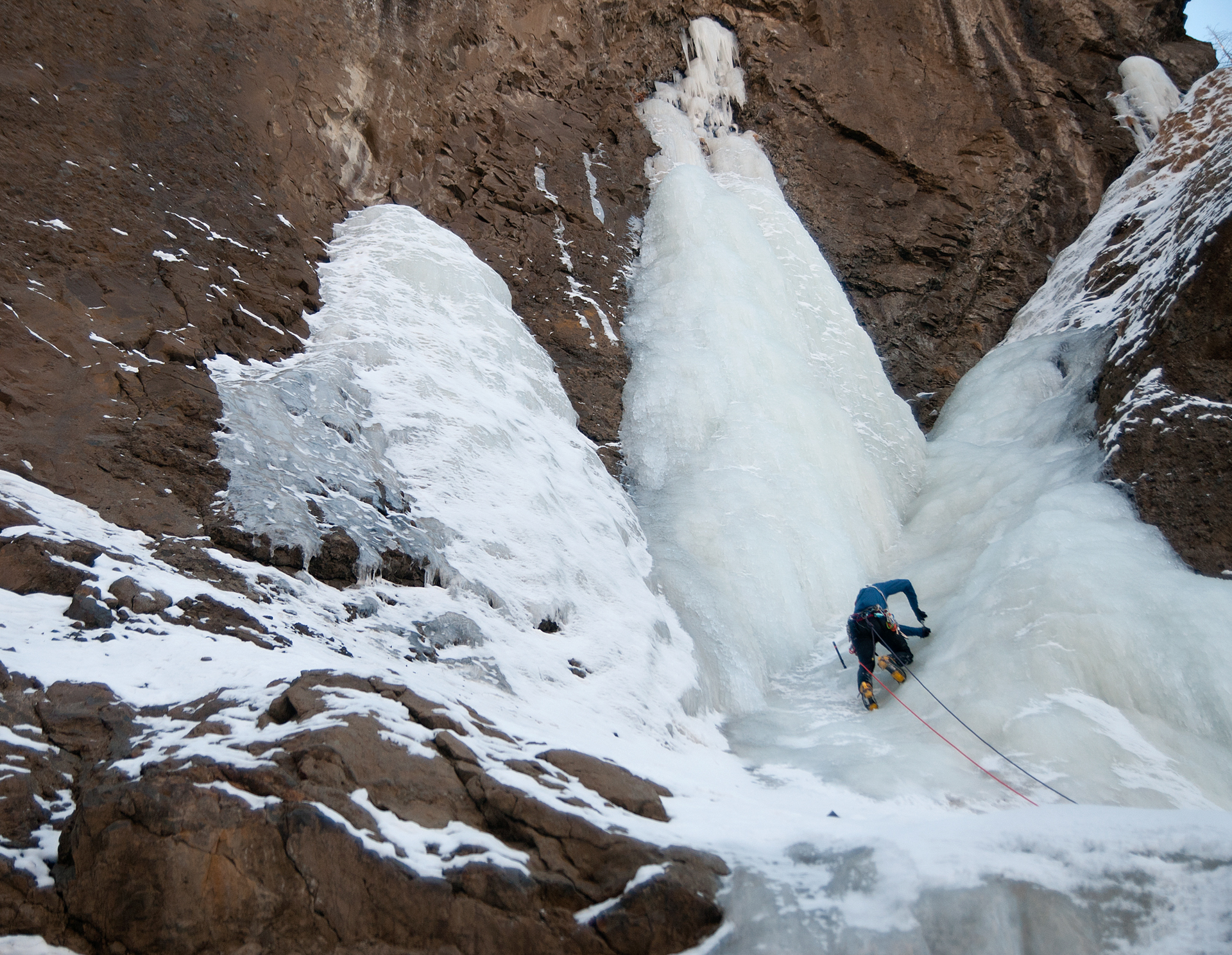 Man climbing a frozen waterfall