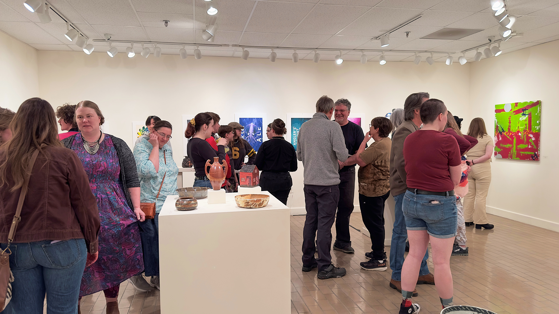 A group of people looking at different types of art in a gallery