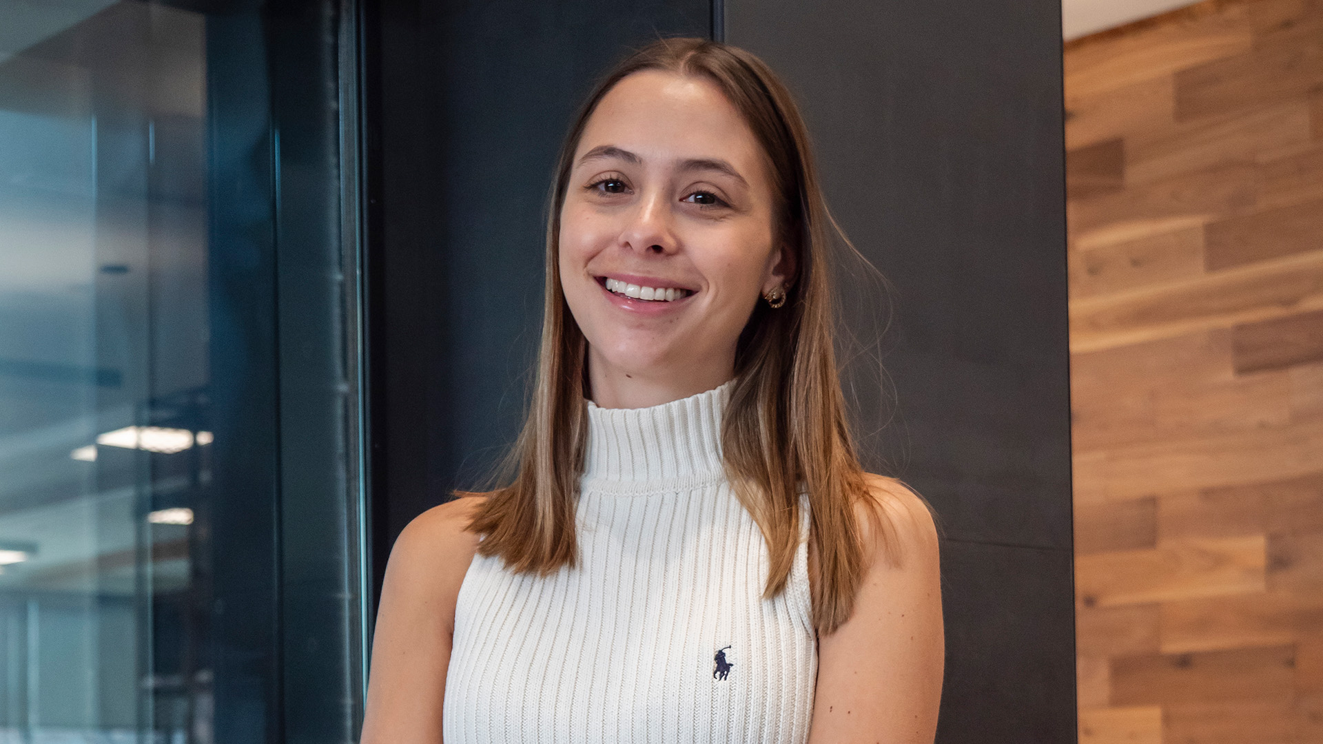 A female college student wearing a white turtleneck sitting in front of a fireplace