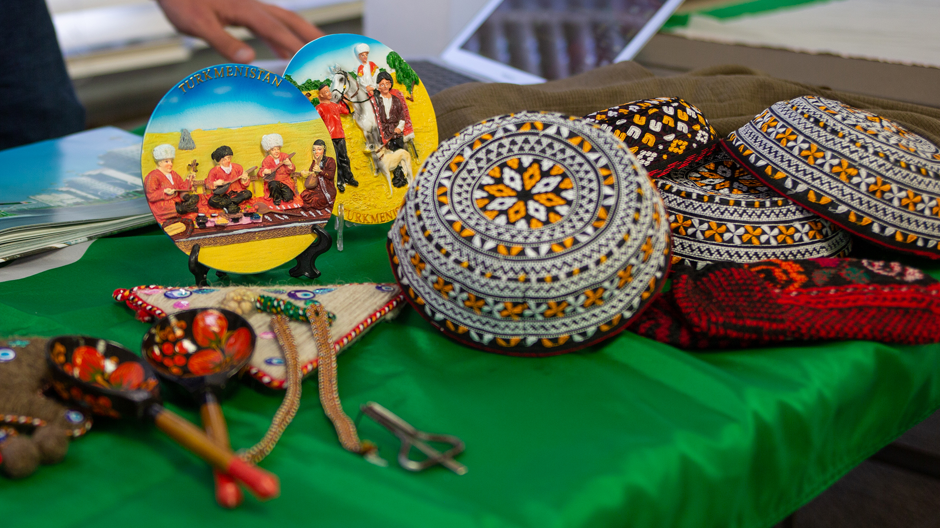 A collection of Turkmen artwork and caps on a table
