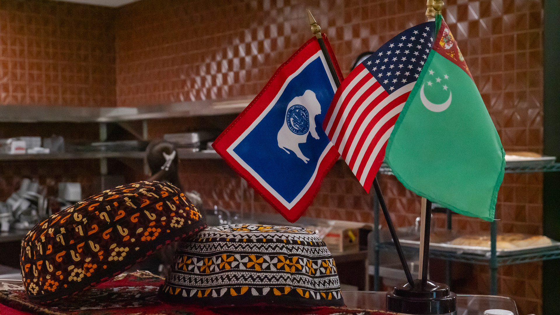 A collection of small Wyoming, U.S., and Turkmen flags with Turkmen head gear on a glass top